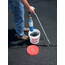 Closeup showing legs of man in jeans holding a torch, heating newly applied black Crack Stix rope to an apsphalt crack